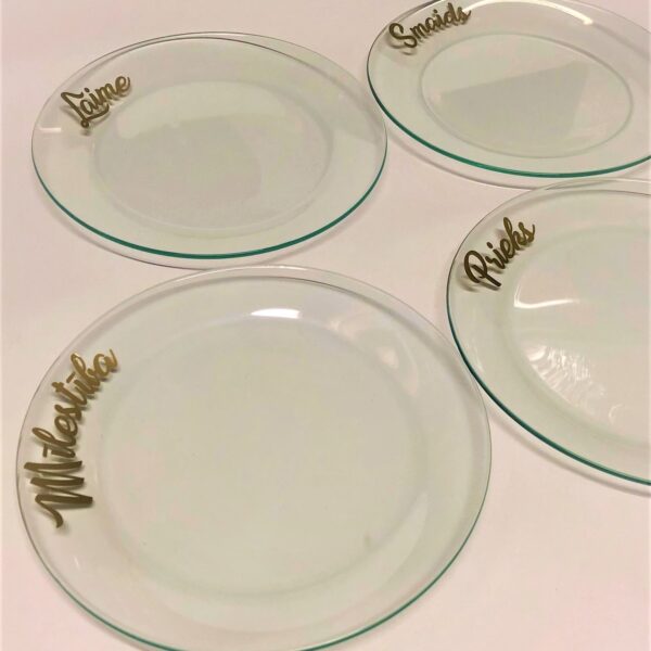 Caurspīdīgi stikla šķīvji ar uzrakstiem.